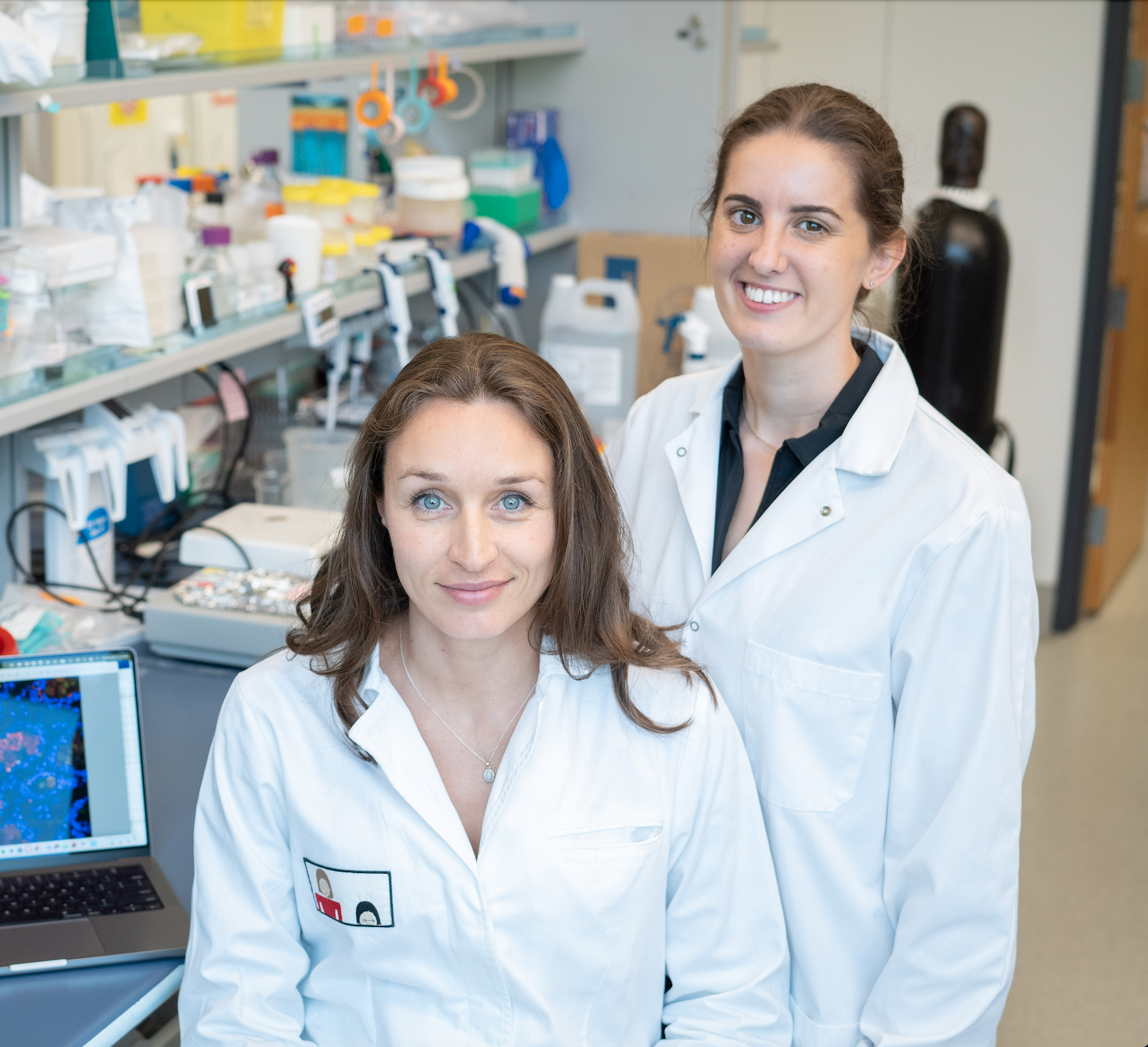 Dr. Carolina Tropini and Sophie Cotton in white lab coats and smiling at the camera.