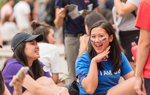 Two students on imagine day with I AM UBC shirts. One is smiling and the other is looking at the person smiling.