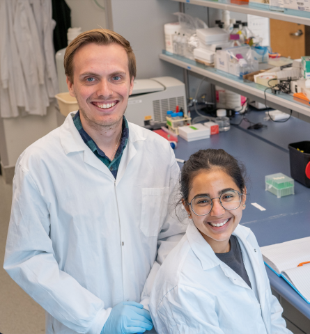 W. Austin Guild and Ananya Saraph wearing white lab coats and smiling at the camera.